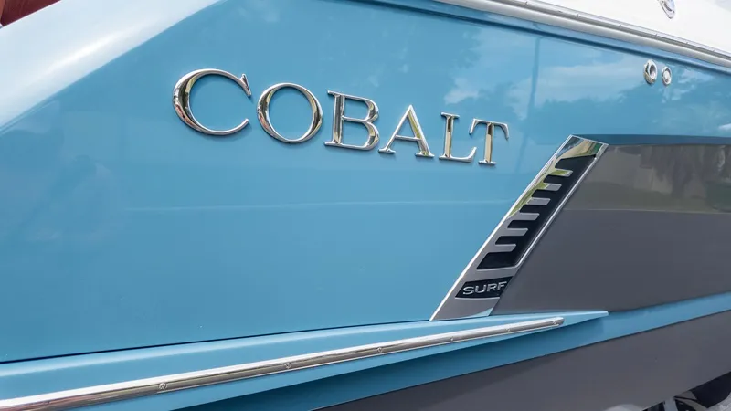 Slide: The Image of Close-up of the blue Cobalt R6 Surf boat with shiny logo. - 30