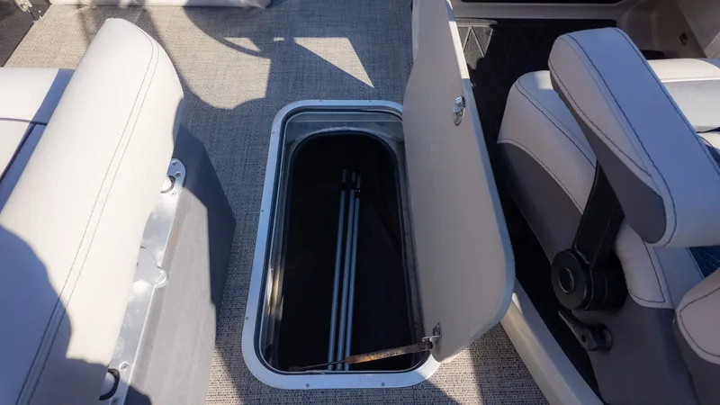 Slide: The Image of An open storage compartment on a boat with gray carpet and white seating. - 17