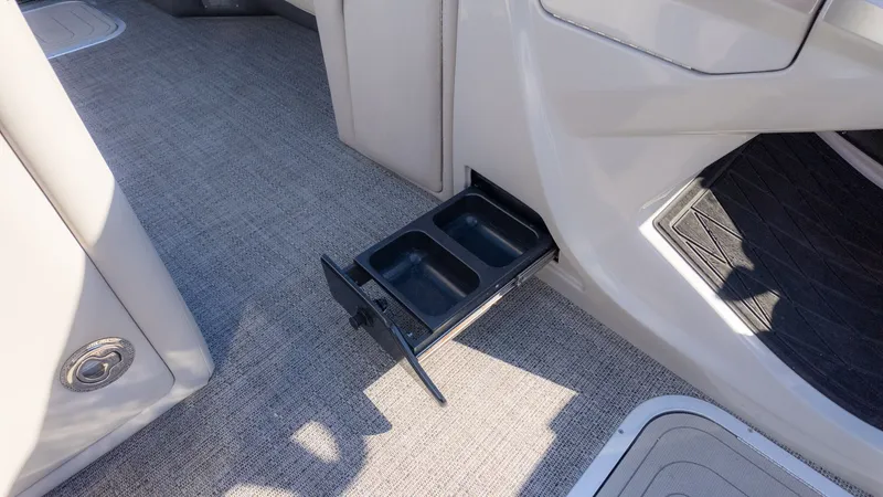 Slide: The Image of A pull-out cup holder on a boat with gray carpet flooring. - 21