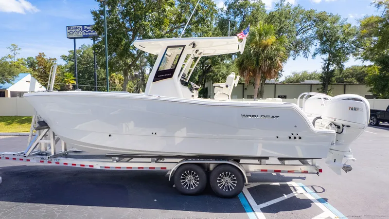 The Image of A 2026 World Cat 265CC boat on a trailer, surrounded by trees and buildings. - 1