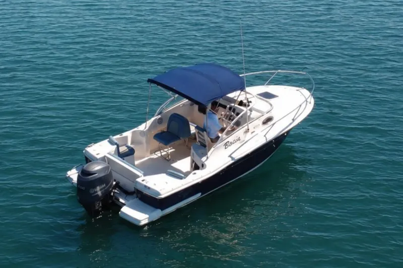 Slide: The Image of 2008 Scout 222 Abaco boat with blue canopy on calm water. - 2