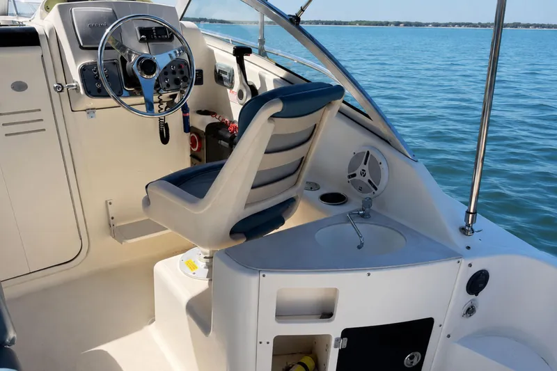 Slide: The Image of 2008 Scout 222 Abaco boat interior with steering wheel and seating, on calm blue water. - 15
