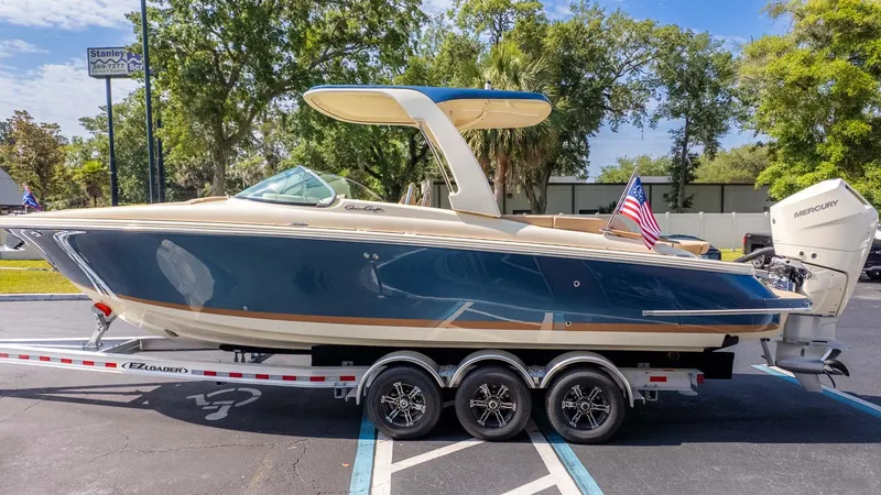 Slide: The Image of A sleek 2025 Chris-Craft Launch 28 GT boat on a trailer, featuring a blue hull and American flag. - 3