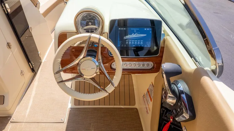 Slide: The Image of The cockpit of a 2025 Chris-Craft Launch 28 GT with a sleek steering wheel and modern instruments. - 28