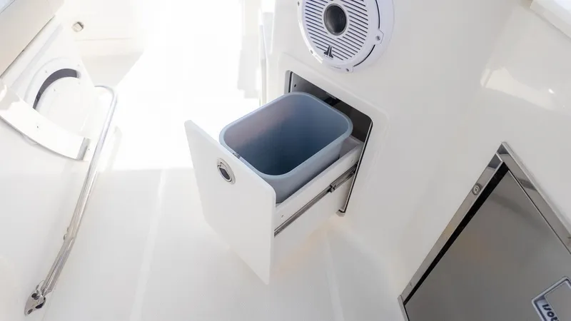 Slide: The Image of An open cabinet with a pull-out trash bin and a speaker above it. - 15
