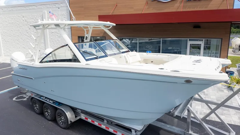 The Image of A World Cat 280 Dual Console boat on a trailer in front of a building. - 1