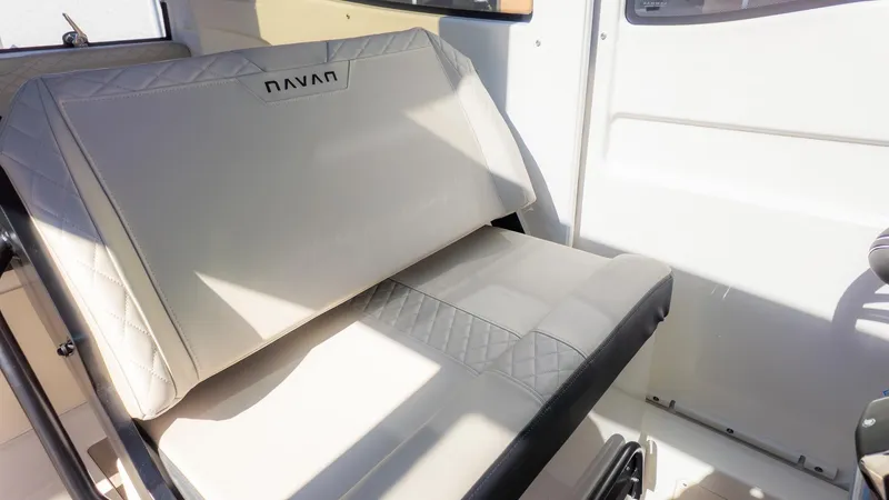 Slide: The Image of Bench seat inside a boat with light upholstery and Navan logo. - 23