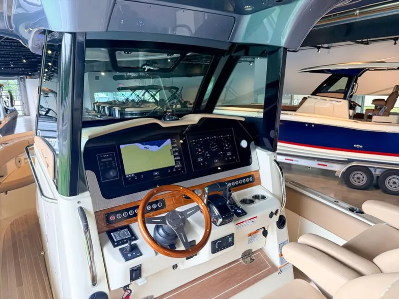 Slide: The Image of The image shows the cockpit of a 2024 Chris-Craft Catalina 30 Heritage Edition. It features a sleek design with a wooden steering wheel and modern navigation systems. Another boat is visible in the background. - 6