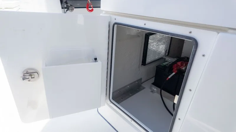 Slide: The Image of An open storage compartment on a boat reveals a battery and cables. - 16