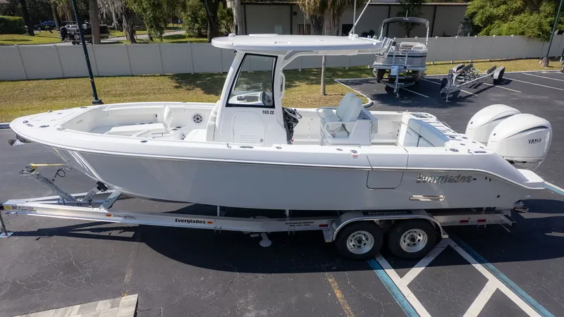 The Image of A white Everglades 285 Center Console boat on a trailer, parked in a lot. - 1