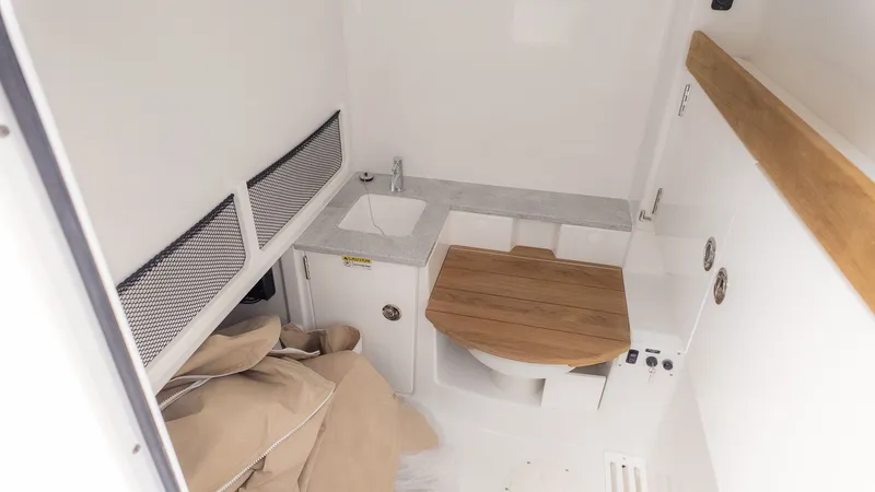 Slide: The Image of Interior of a boat cabin with a sink and toilet, surrounded by white walls and wood accents. - 13