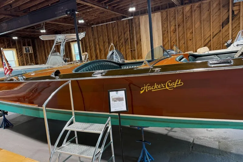 Slide: The Image of 1996 Hacker-Craft Triple Cockpit Runabout in wooden interior showroom, showcasing classic boat design. - 14