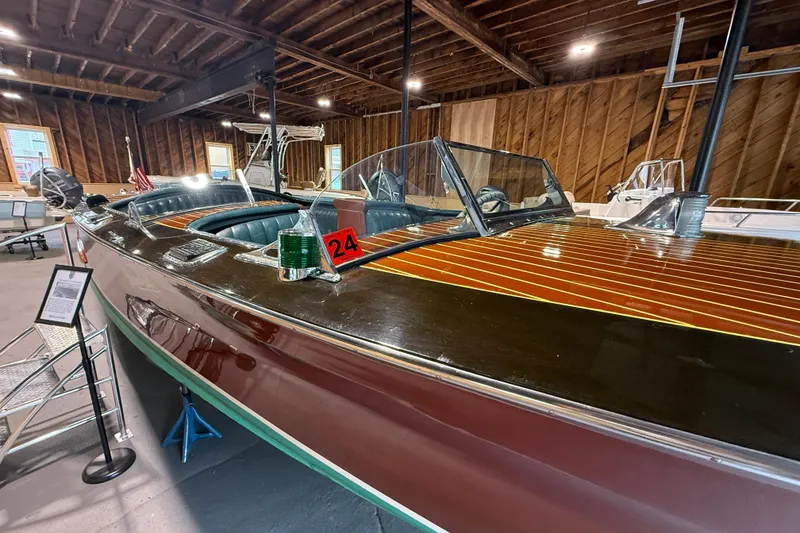 The Image of 1996 Hacker-Craft Triple Cockpit Runabout in wooden interior showroom, showcasing classic design. - 0