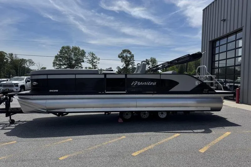 Slide: The Image of 2026 Manitou Encore 25 SL SHP pontoon boat parked outdoors near a building. - 4