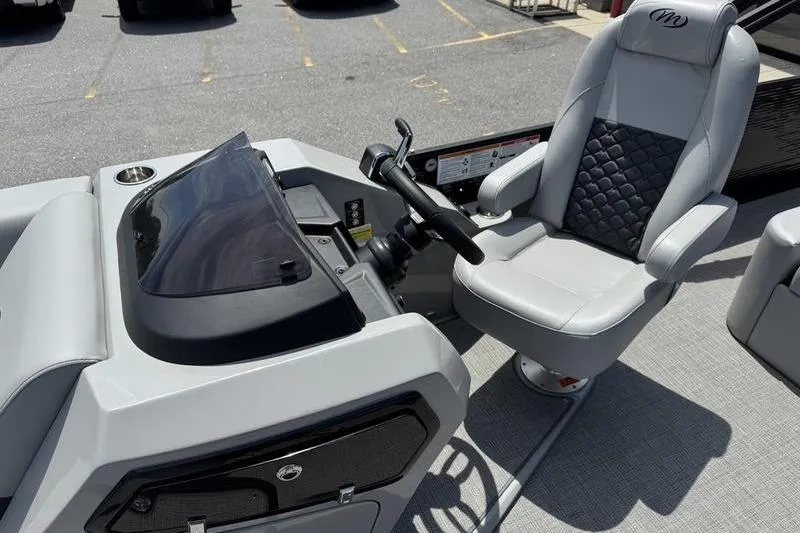 Slide: The Image of 2026 Manitou Encore 25 SL SHP boat cockpit with steering wheel and captain's chair. - 10