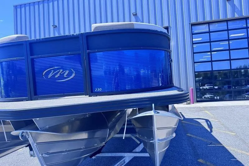 Slide: The Image of 2027 Manitou Aurora 23 RF SHP pontoon boat parked outside a modern building. - 16