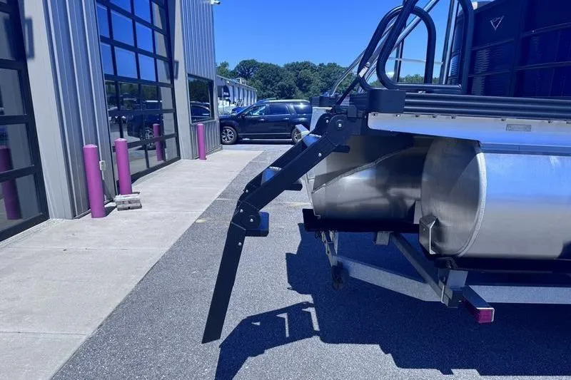 Slide: The Image of 2027 Manitou Aurora 23 RF SHP pontoon boat detail near a modern building. - 7