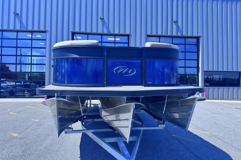 Slide: The Image of 2027 Manitou Aurora 23 RF SHP pontoon boat on trailer, parked outside industrial building. - 3