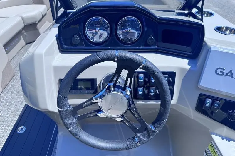 Slide: The Image of Steering wheel and dashboard of 2027 Manitou Aurora 23 RF SHP boat. - 24