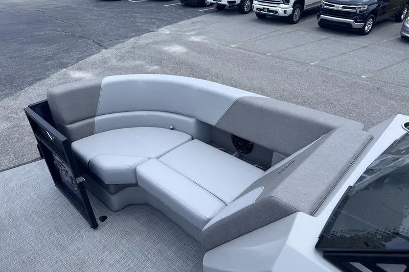 Slide: The Image of 2027 Manitou Aurora 23 SL SHP boat interior with gray seating in a parking lot. - 21