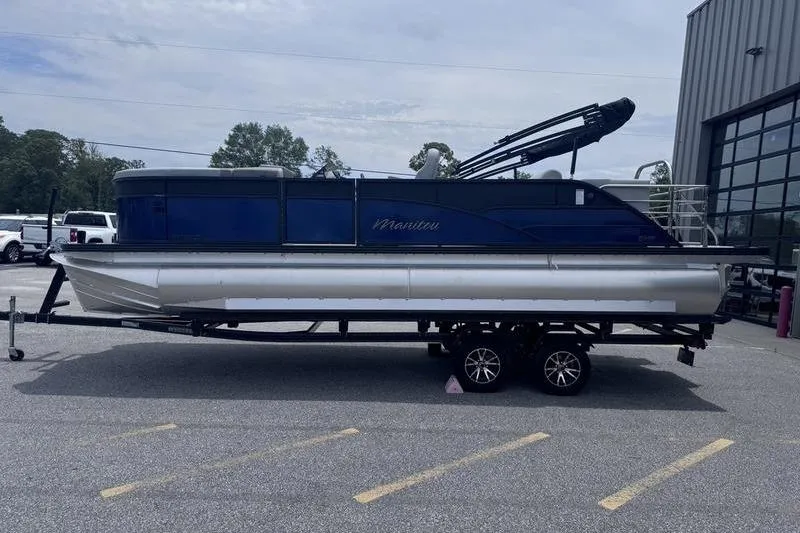 The Image of 2027 Manitou Aurora 23 SL SHP pontoon boat on trailer, parked outdoors. - 1