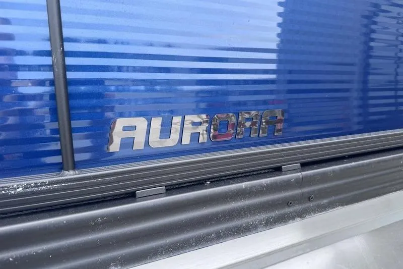 Slide: The Image of 2027 Manitou Aurora 23 SL SHP boat with blue exterior and chrome logo. - 15
