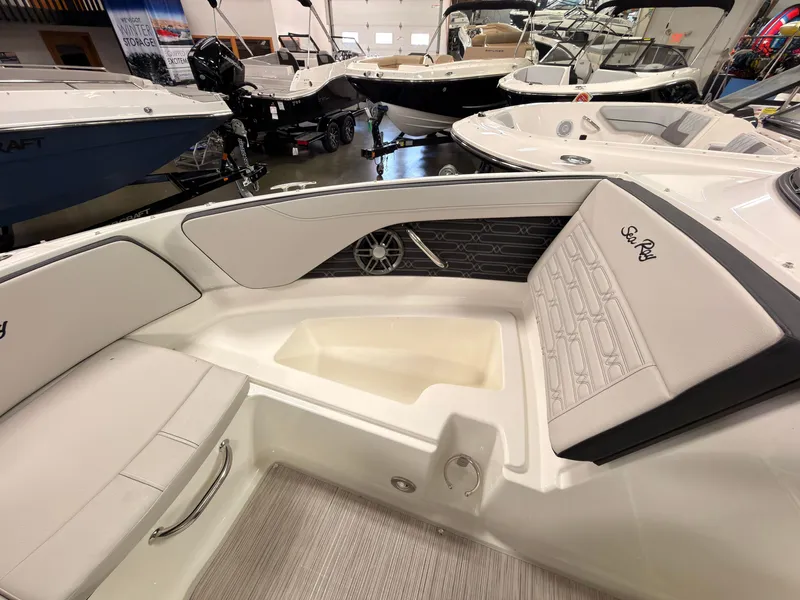 Slide: The Image of The image shows the interior of a 2026 Sea Ray SPX 210 boat. It features white upholstery and a modern design. - 44