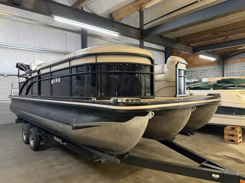 The Image of A 2015 Bennington 24 SLX3 pontoon boat on a trailer in a storage facility. - 1