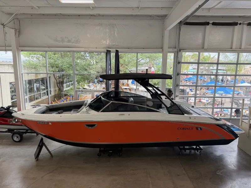 The Image of An orange 2022 Cobalt R30 boat is displayed in a showroom. - 1