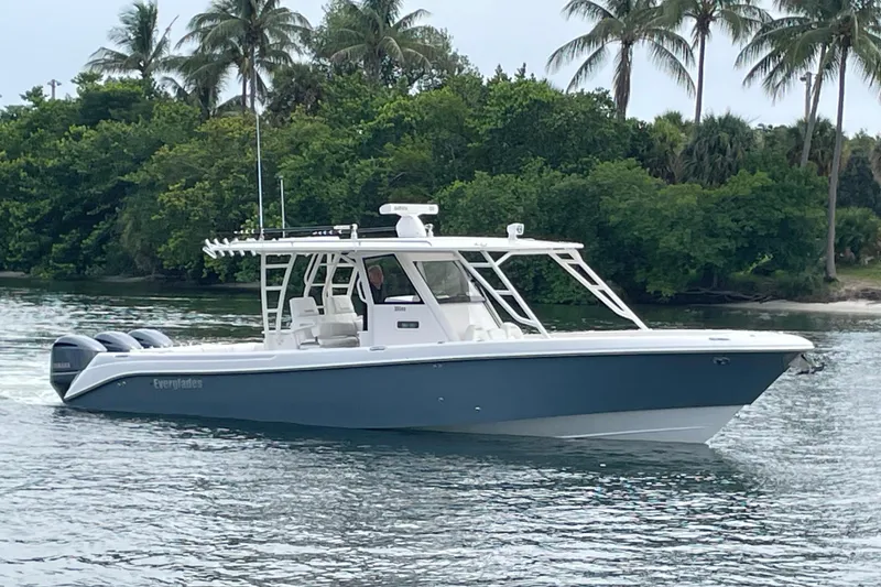 The Image of 2015 Everglades 355CCX boat cruising on water with lush greenery and palm trees in the background. - 0