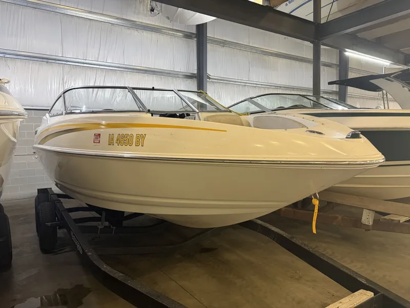 The Image of A 2007 Larson Senza 206 boat is on a trailer in a warehouse. - 1