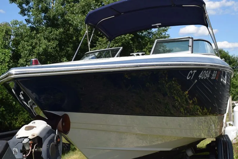 Slide: The Image of 2006 Cobalt 240 boat with canopy, parked on trailer, surrounded by trees. - 2