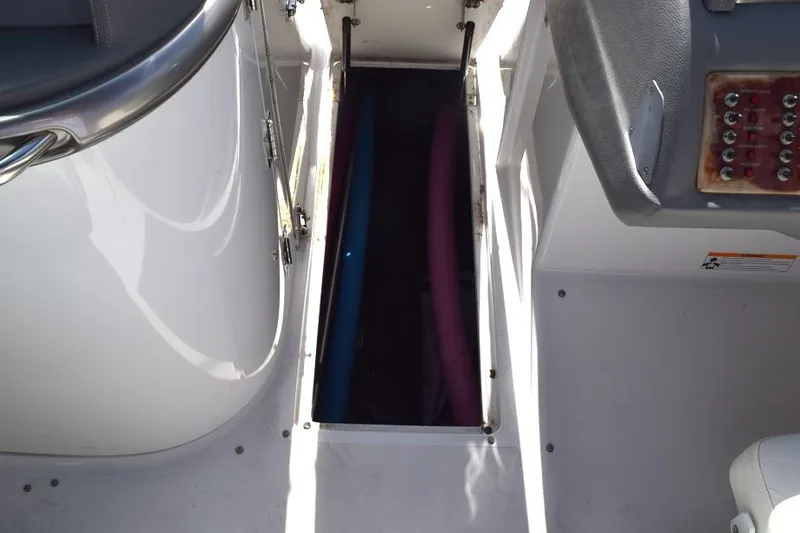 Slide: The Image of Storage compartment on a 2006 Cobalt 240 boat with visible pool noodles. - 19