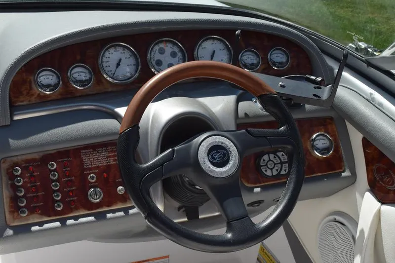 Slide: The Image of Steering wheel and dashboard of a 2006 Cobalt 240 boat with wood accents and gauges. - 6
