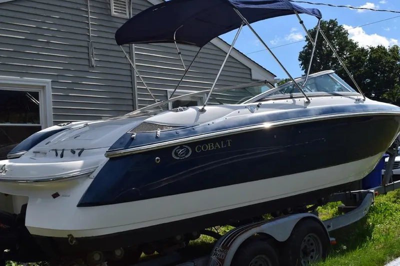 Slide: The Image of 2006 Cobalt 240 boat with blue canopy on trailer, parked beside a house. - 4