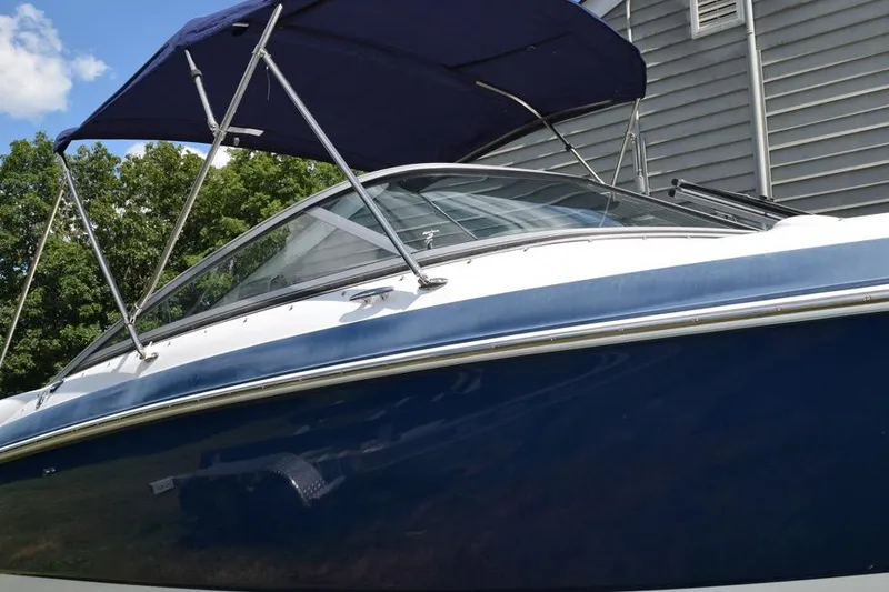 Slide: The Image of 2006 Cobalt 240 boat with blue hull and canopy, parked near a building. - 3