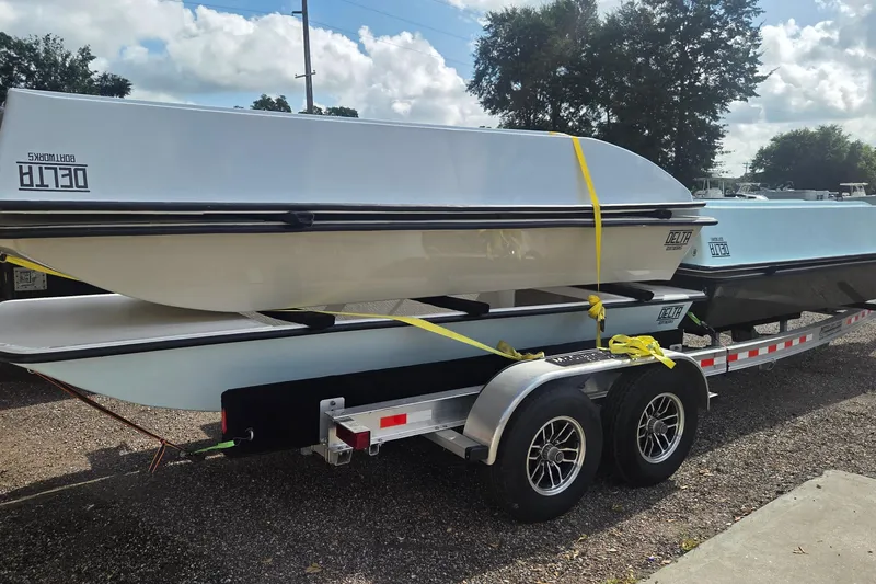 Slide: The Image of 2027 Delta Boatworks 1550 on trailer, secured with yellow straps, under a cloudy sky. - 3