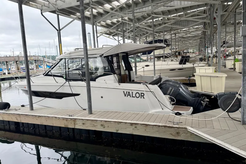 Slide: The Image of 2023 Jeanneau NC Weekender 895 docked in a marina under a covered structure. - 2