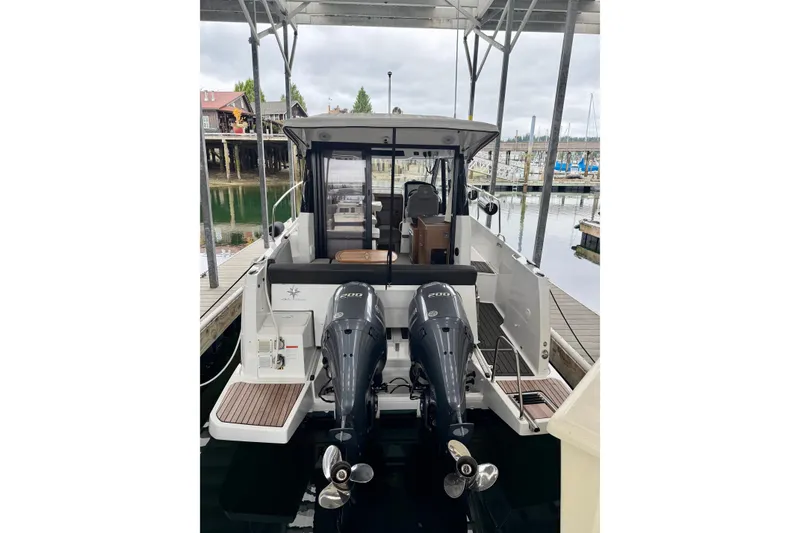 Slide: The Image of 2023 Jeanneau NC Weekender 895 docked, featuring dual outboard engines and spacious deck. - 4