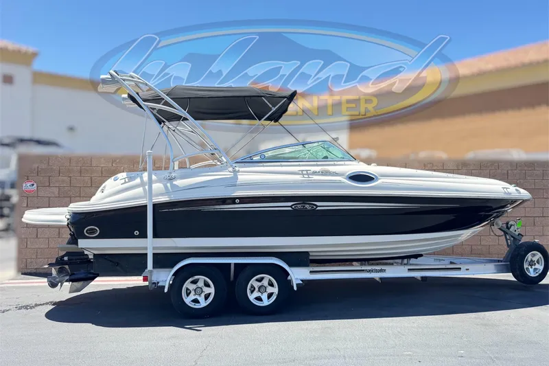 The Image of 2007 Sea Ray 240 Sundeck boat on trailer, parked outdoors, with bimini top. - 0