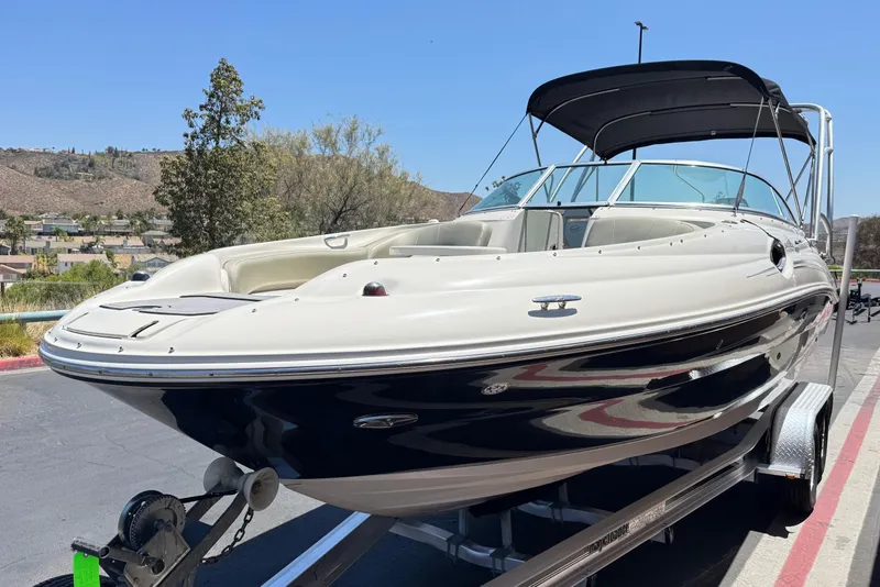 Slide: The Image of 2007 Sea Ray 240 Sundeck boat on trailer, parked outdoors under clear blue sky. - 3