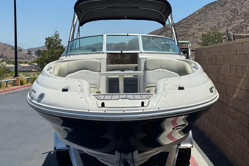 Slide: The Image of 2007 Sea Ray 240 Sundeck boat on trailer, parked near a brick wall. - 2