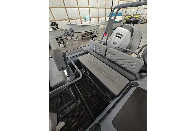 Slide: The Image of 2023 Highfield Patrol 600 boat interior with diamond-stitched seating in a storage facility. - 8
