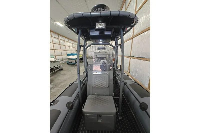Slide: The Image of 2023 Highfield Patrol 600 boat interior with seating and navigation equipment in a storage facility. - 5
