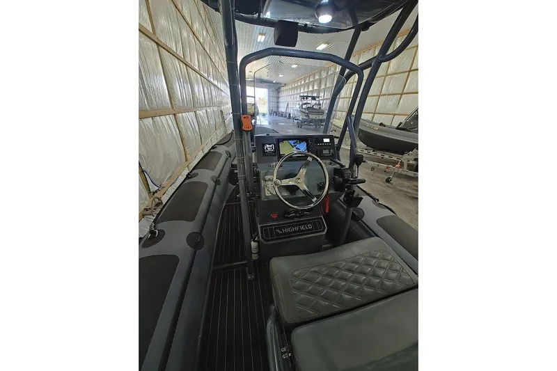 Slide: The Image of 2023 Highfield Patrol 600 boat interior with steering wheel and control panel in a warehouse. - 3