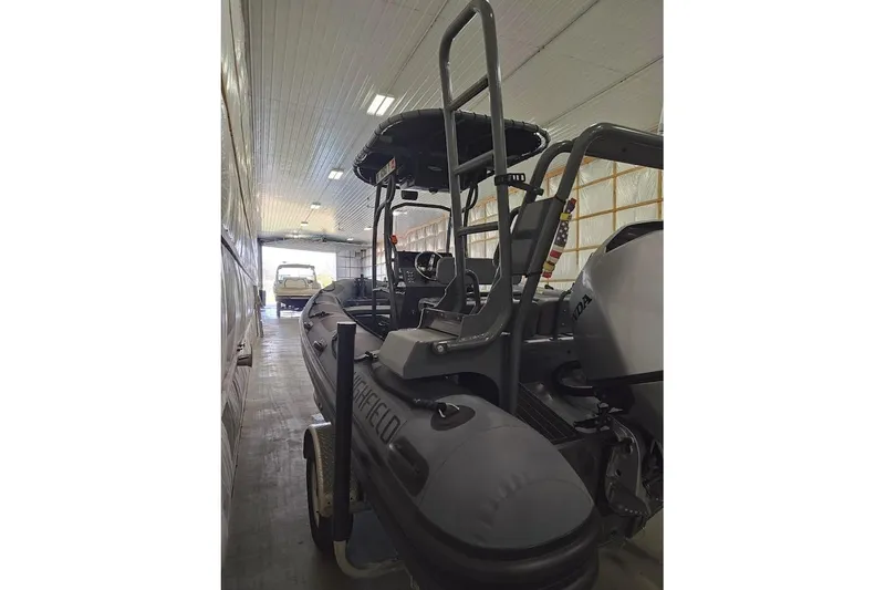 Slide: The Image of 2023 Highfield Patrol 600 boat in a storage facility, featuring a Honda outboard motor. - 13