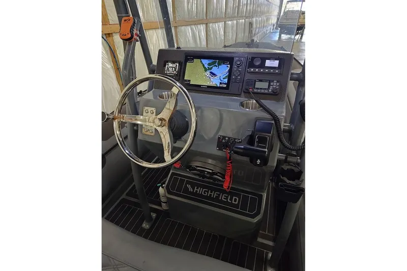 Slide: The Image of 2023 Highfield Patrol 600 boat dashboard with steering wheel and navigation system. - 2