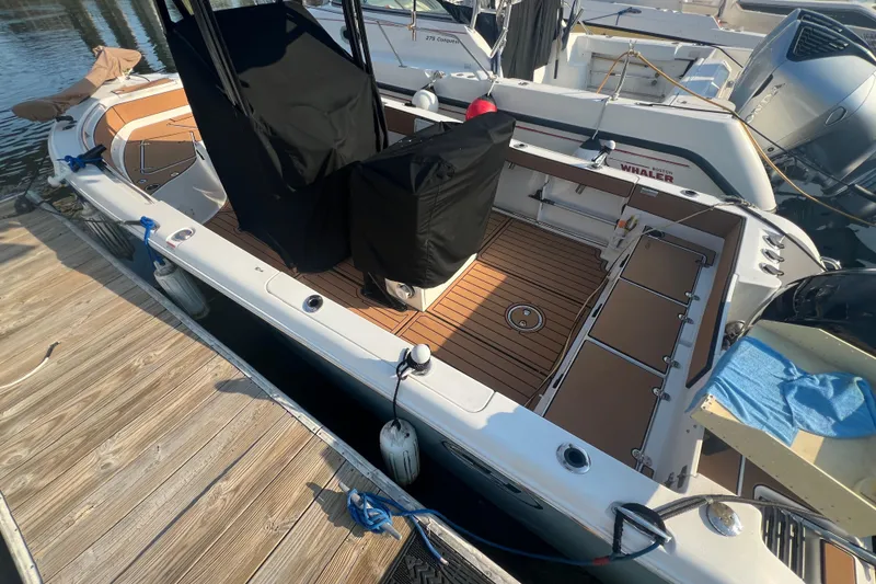 Slide: The Image of 2019 Sea Hunt Ultra 234 boat docked, featuring a spacious deck and covered seating. - 4