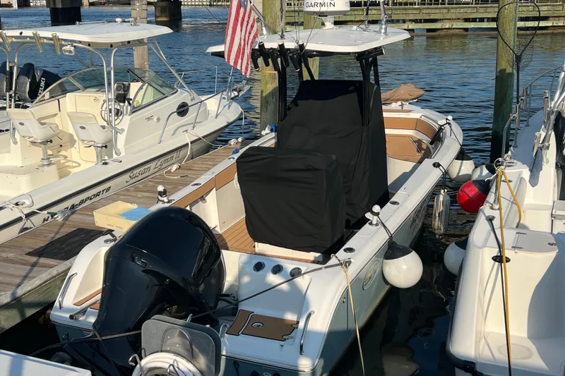 Slide: The Image of 2019 Sea Hunt Ultra 234 boat docked with protective covers and American flag. - 21
