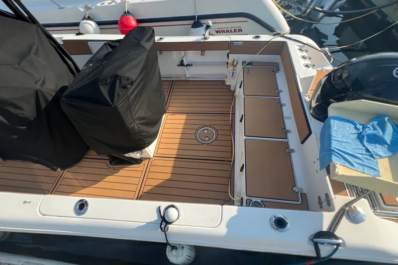 Slide: The Image of 2019 Sea Hunt Ultra 234 boat deck with wood finish and covered equipment. - 6